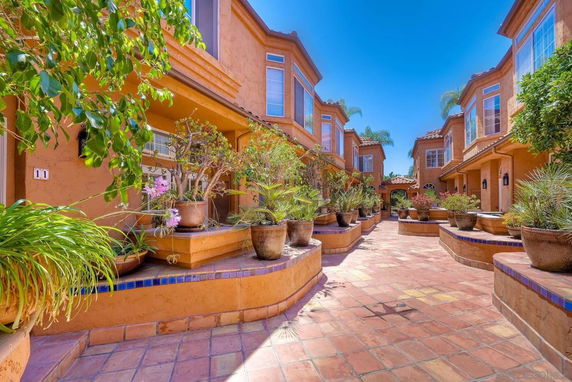 Front view of a multi-story townhouse with terracotta-colored walls and large windows.