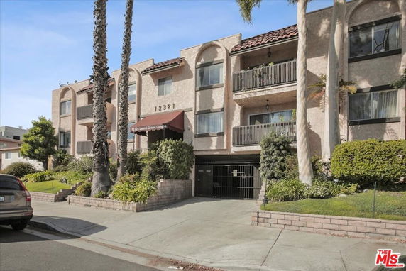 Front view of a multi-story condominium building with balconies and a parking entrance.
