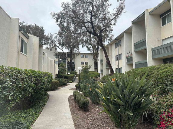 Front view of a multi-story apartment complex with landscaped pathway.