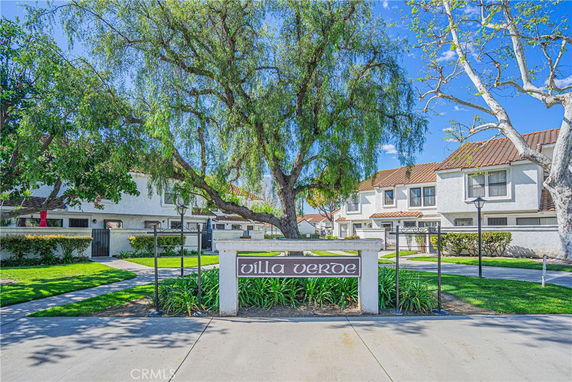 Front view of a residential complex with multiple two-story buildings and a large tree.