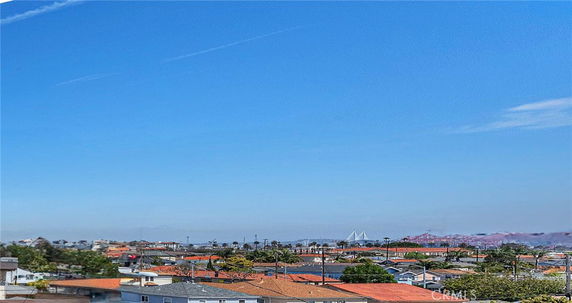 Wide angle view of rooftops and distant structures under a clear blue sky.