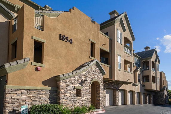 Front view of a multi-story residential building with balconies and garages.