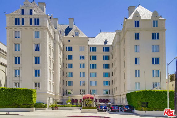 Front view of a multi-story residential building with a symmetrical design and a gated entrance.