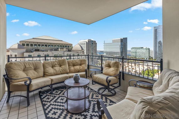 Outdoor seating area on a balcony with a panoramic view of the surrounding cityscape.