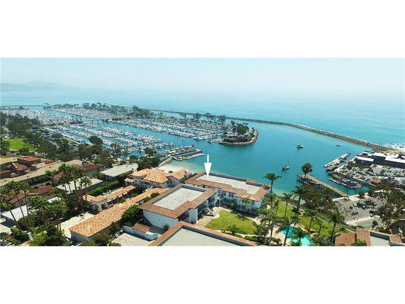 Aerial view of a coastal area with buildings, marina, and ocean.
