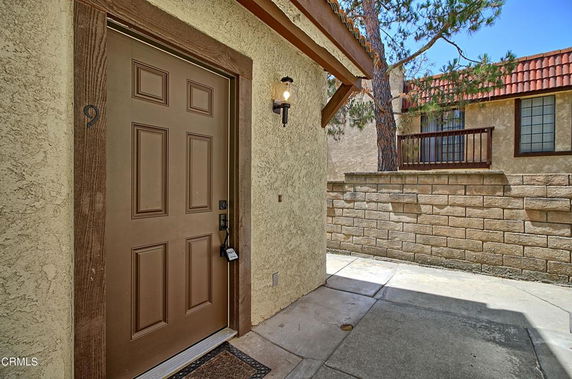 Front view of a house entrance with a brown door and outdoor lamp.