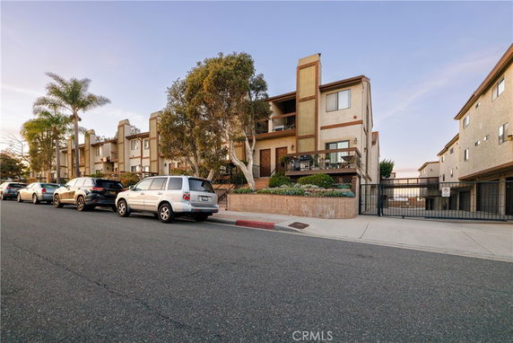 Front view of a multi-story residential building with balconies and a gated entrance.