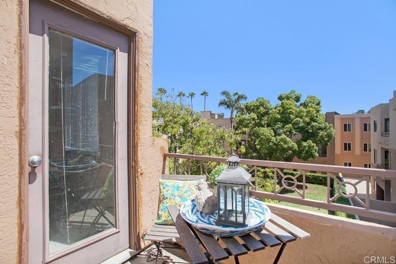 Balcony view from a building overlooking other residential structures and trees.