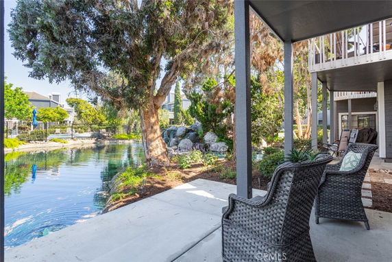 Outdoor view from the patio of a building overlooking a pond with surrounding trees and residential structures.