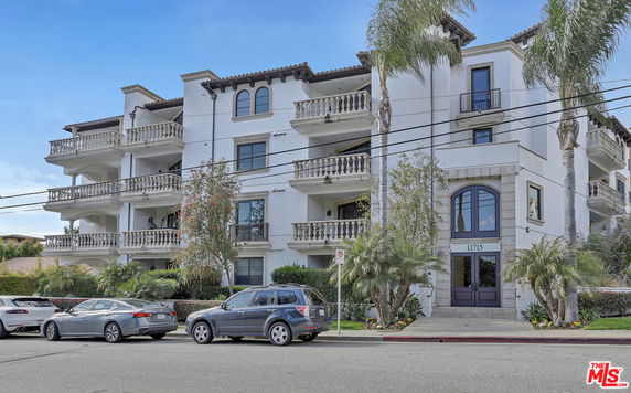 Front view of a multi-story residential building with balconies and a central entrance.