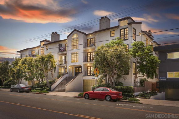 Front view of a multi-story residential building with multiple balconies and large windows.