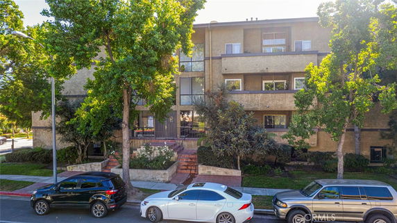 Front view of a multi-story apartment building with a central entrance and balconies.