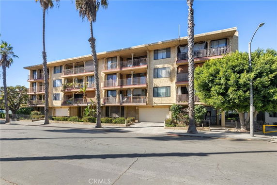 Front view of a multi-story apartment building with balconies and garage entrance.