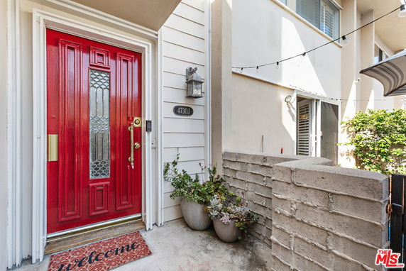 Front view of a house entrance with a red door and potted plants.