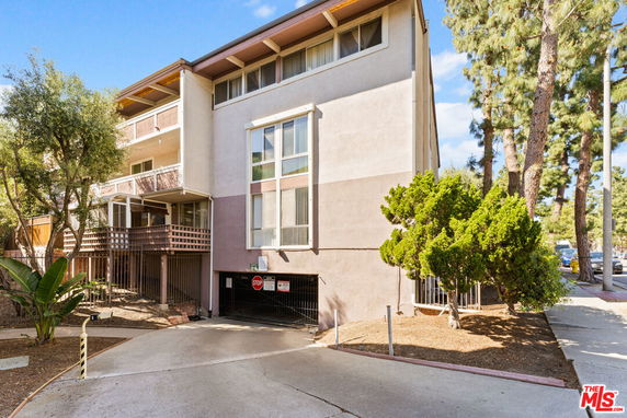 Front view of a multi-story residential building with balconies and large windows.