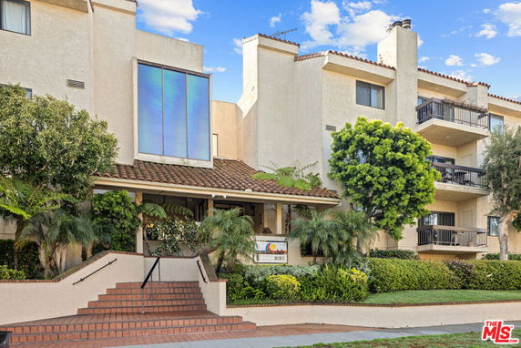 Front view of a multi-story building with balconies and steps leading to the entrance.
