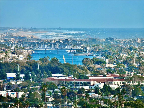 Panoramic view of a coastal city with distant ocean and boats.