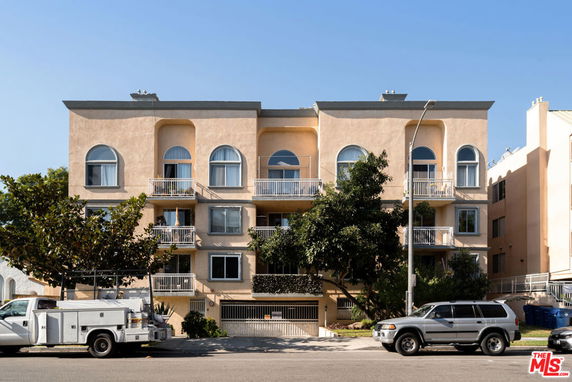 Front view of a multi-story residential building with balconies and arched windows.