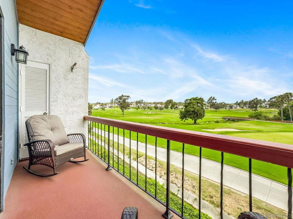 Balcony view overlooking a golf course with a chair on the balcony.