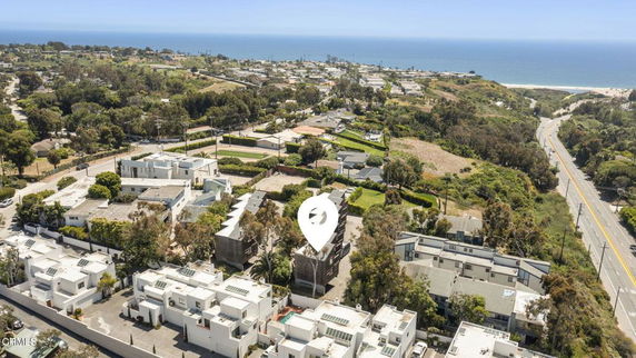 Aerial view of a coastal residential area with modern houses and a coastline visible in the distance.