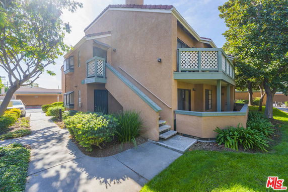 Front view of a two-story house with an exterior staircase and balcony.