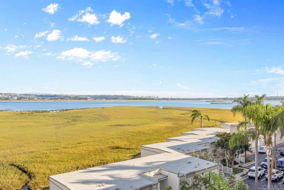 Scenic view overlooking a body of water and grassy wetlands with houses below.
