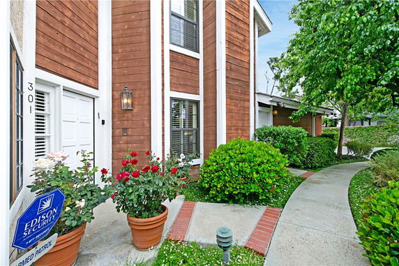 Front view of a house with wooden paneling and potted plants at the entrance.