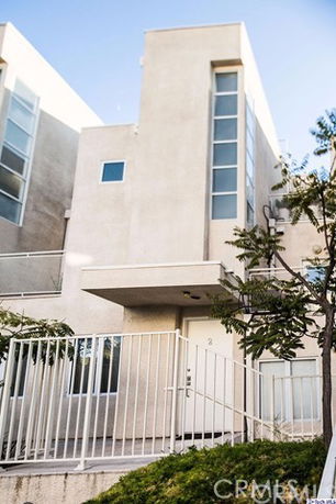 Front view of a modern multi-story building with large windows and a gated entrance.
