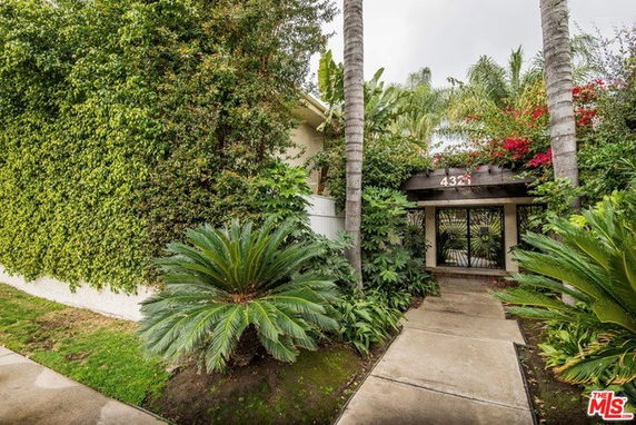 Front view of a house with a lush garden and walkway.