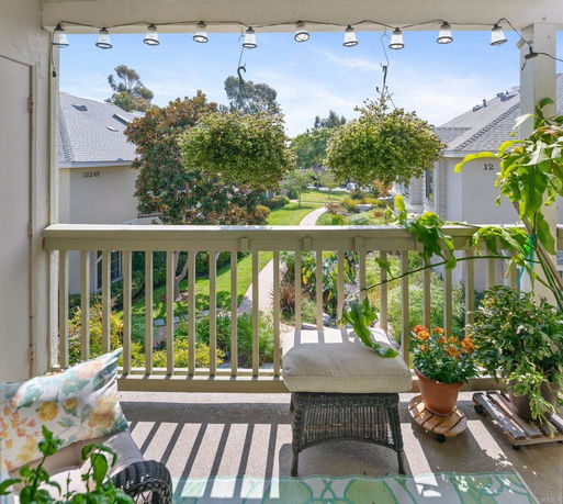 View from a balcony overlooking a landscaped area with greenery and neighboring buildings.