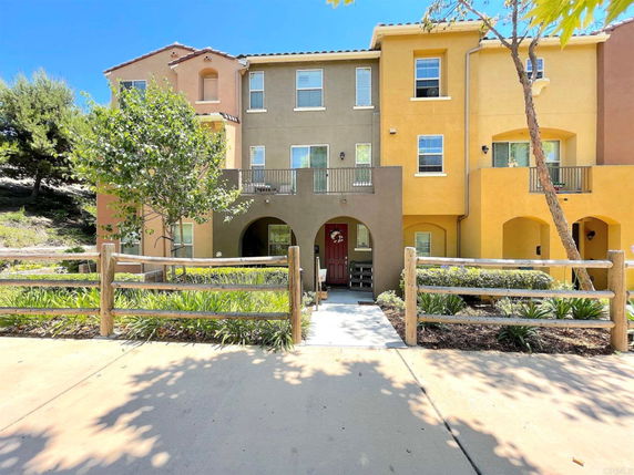 Front view of a three-story residential building with multiple entrances and modest landscaping in front.