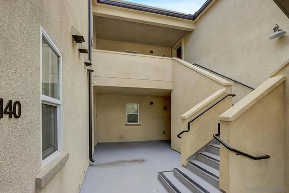 Front view of a multi-story building with stairs and a balcony.