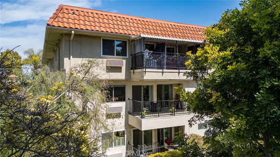 View of a multi-story building with balconies and a tiled roof.