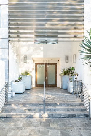 Front view of a modern building entrance with double glass doors and metal railing.