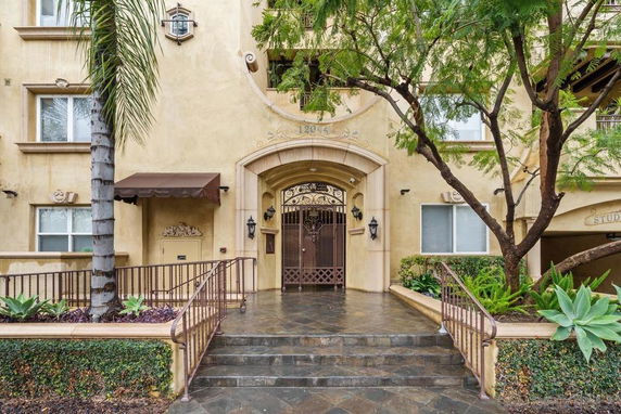 Front view of a multi-story building with an arched entrance and wrought iron gate.