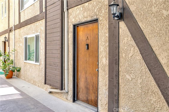 Exterior view of a building hallway with a wooden door labeled 'A' and a window.