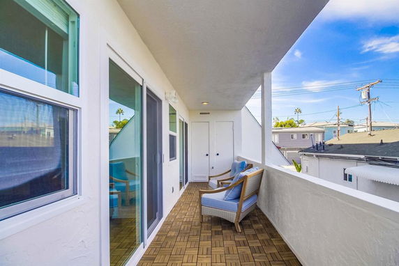 Outdoor balcony with chairs overlooking neighboring buildings and rooftops.