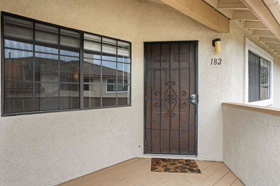 Entrance area of a house with a metal door and window beside it.