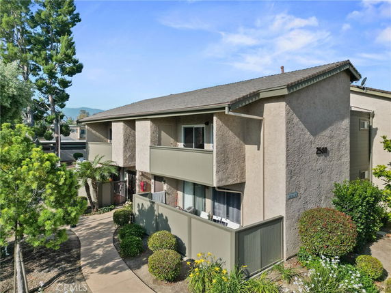 Front view of a two-story residential building with balconies and a sloped roof.