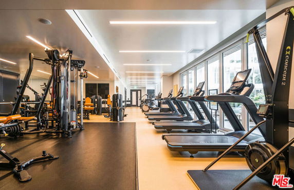 Interior view of a gym with exercise equipment, including treadmills and weight machines.