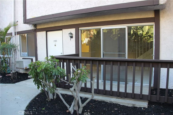 Front view of a residential building entrance with a brown railing and sliding glass door.
