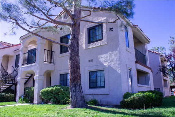 Front view of a two-story apartment building with balconies and a staircase.
