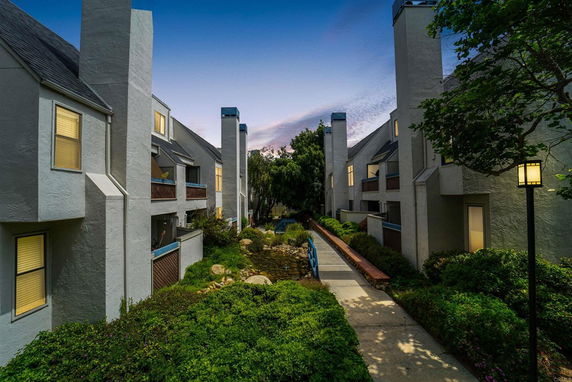 Front view of multi-story residential buildings with illuminated windows and pathway.