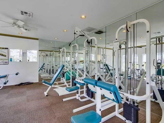 Gym area with exercise machines and mirrored walls.