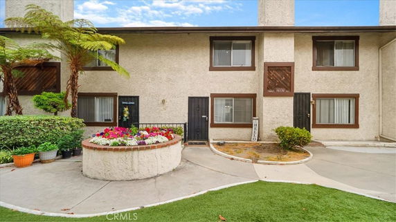 Front view of a two-story residential building with a flower bed and small garden area.