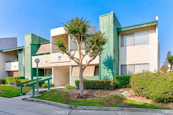 Front view of a multi-story residential building with green accents and large windows.