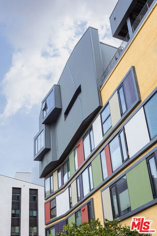 Front view of a modern multi-story building with colorful panels and protruding geometric structures.