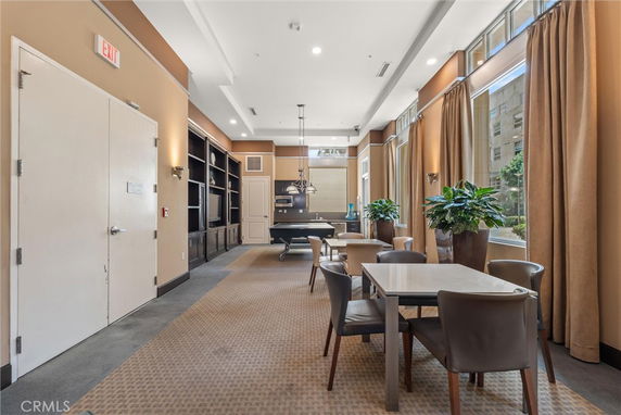 Recreational room with pool table and seating area with large windows.