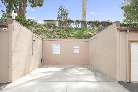 Outdoor car wash area with beige walls and concrete floor.