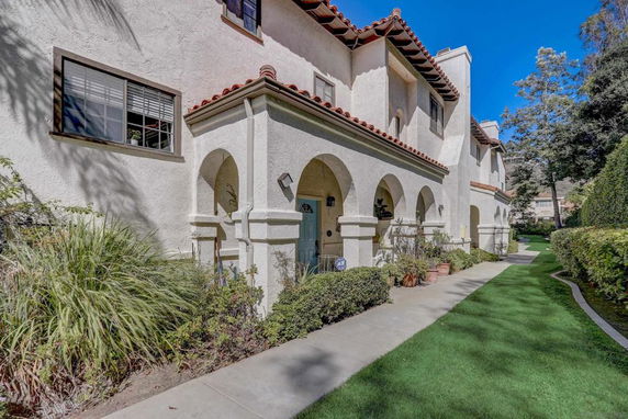 Side view of a multi-story building with arched entryways and red-tiled roof.